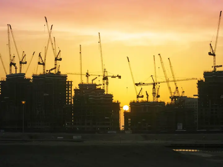 روافع إنشائية في مشروع تطوير بالإمارات عند الغروب